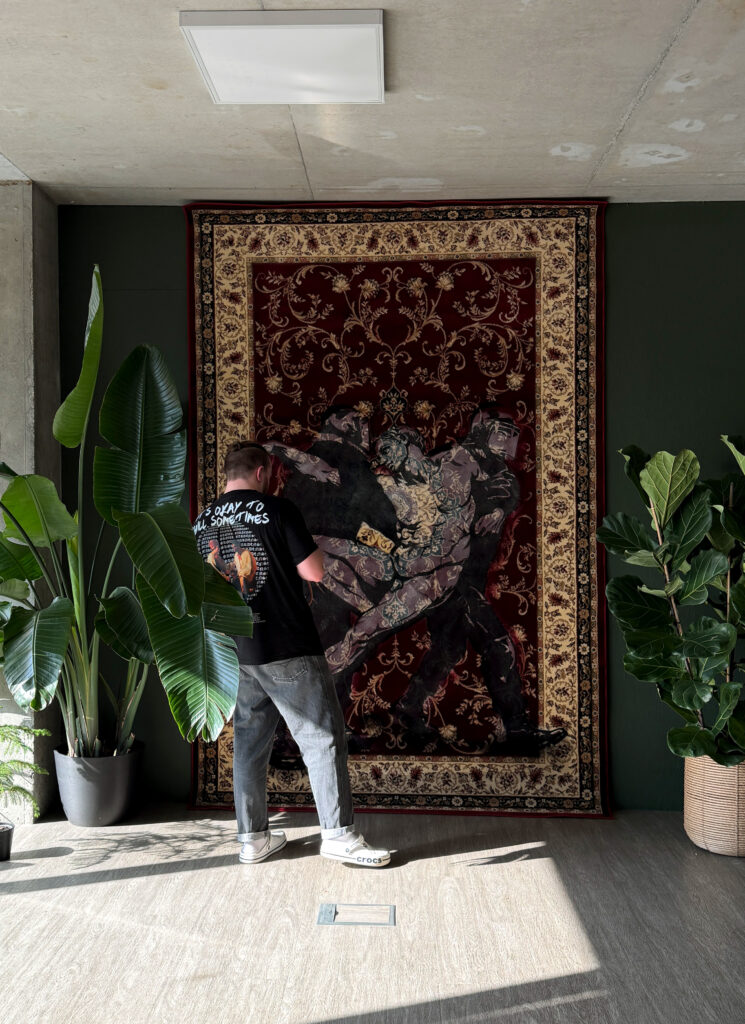 Drovianni in the studio, facing a painted rug